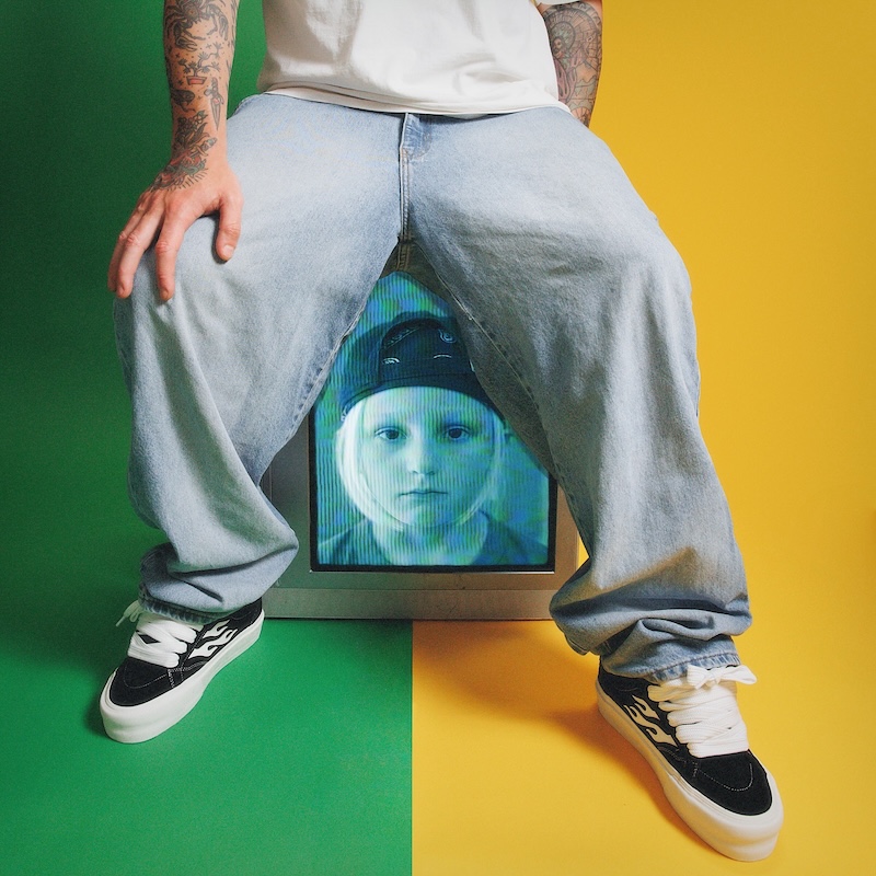 bodie's lower body sitting on an old TV with a fuzzy blue image of a kid who looks like a young version of him